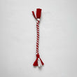 Red and white braided fleece fabric dog tug toy, laid flat on white background