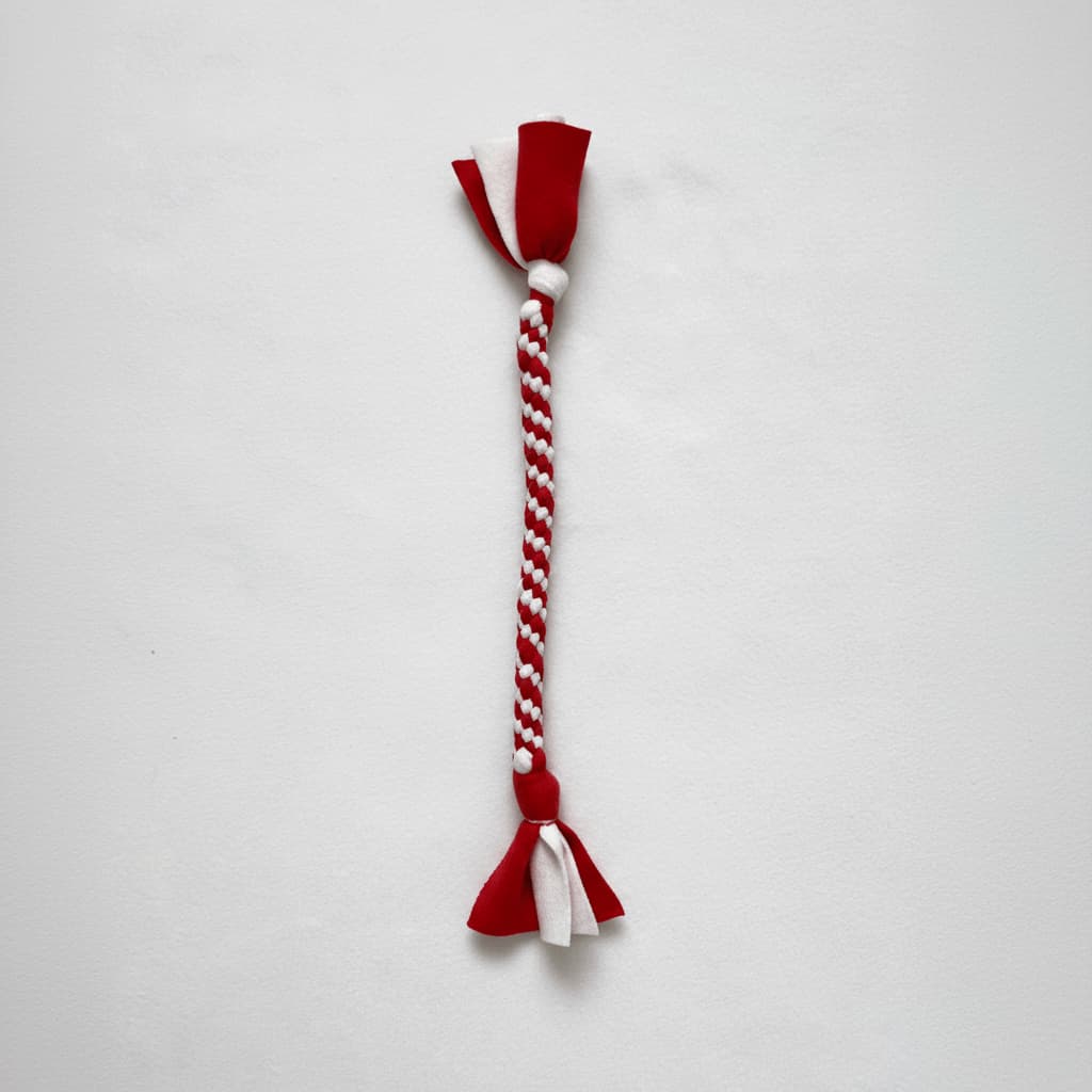 Red and white braided fleece fabric dog tug toy, laid flat on white background